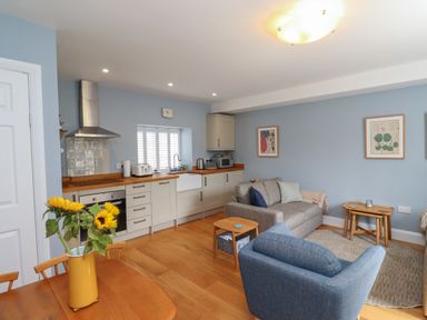 A kitchen and living area with wooden floor and blue walls at Lark Rise in Alnmouth