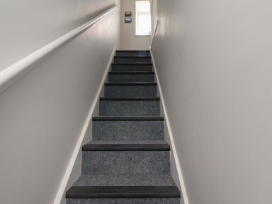 A carpeted staircase with gray steps and handrail leading to a window at Lark Rise in Alnmouth