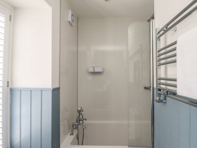 A bathroom with a bathtub shower enclosure and towel rail at Lark Rise in Alnmouth