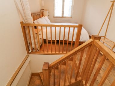 A bedroom with a bed bedside tables and a wooden clothes rack at The Loft Cottage in Totnes
