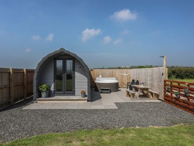 A small pod with double doors a hot tub and outdoor seating area at Nebo Pod in Amlwch