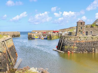 A harbor with boats docked and a stone tower at Nebo Pod in Amlwch