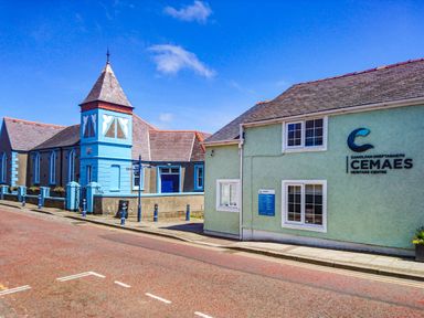 A street view with buildings including Cemaes Heritage Centre and a blue tower at Nebo Pod in Amlwch