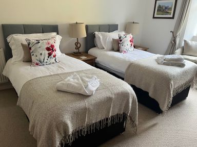 A bedroom with two single beds side by side with lamps on bedside tables in between at The Indigo House in Berwick-Upon-Tweed