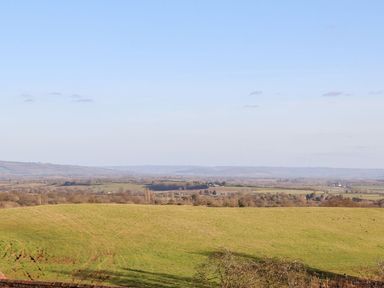 A rural landscape with green fields and distant hills under a clear sky at The Millhouse in Ledbury near Welland