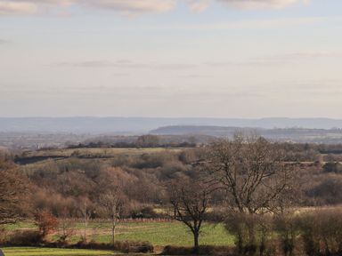 A landscape with fields trees and hills under a cloudy sky at The Millhouse in Ledbury near Welland