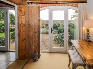 A room with a wooden table and lamp next to glass doors leading to a garden at The Millhouse in Ledbury near Welland