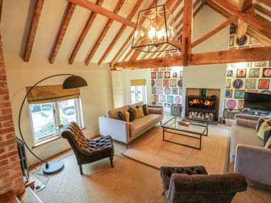 A living room with exposed wooden beams a fireplace sofas armchairs and a glass coffee table at The Millhouse in Ledbury near Welland