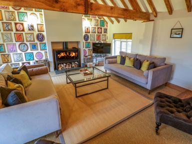 A sitting room with two sofas a glass coffee table a fireplace and a television at The Millhouse in Ledbury near Welland