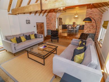 A living room with two sofas a glass coffee table and a dining area at The Millhouse in Ledbury near Welland