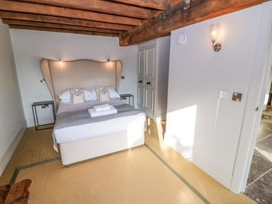 A bedroom with a bed with two pillows and towels on it under exposed wooden beams at The Millhouse in Ledbury near Welland