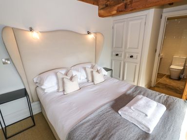 A bedroom with a bed pillows bedside tables and an ensuite bathroom at The Millhouse in Ledbury near Welland
