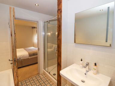 A bathroom with a sink mirror and shower opening to a bedroom at The Millhouse in Ledbury near Welland
