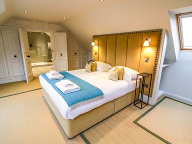 A bedroom with a large bed blue throw towels bedside lamps and an en suite bathroom at The Millhouse in Ledbury near Welland