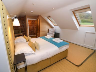 A bedroom with a double bed and pillows two skylight windows and an armchair at The Millhouse Ledbury near Welland