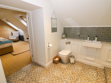 A bathroom with a toilet sink mirror and patterned floor tiles at The Millhouse in Ledbury near Welland