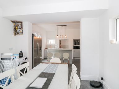 A dining area with a table and chairs leading to a kitchen with an island and bar stools at Castle Manor in Scarborough