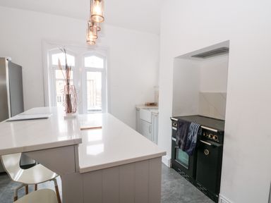 A kitchen with a countertop island stools a black stove and a window at Castle Manor in Scarborough
