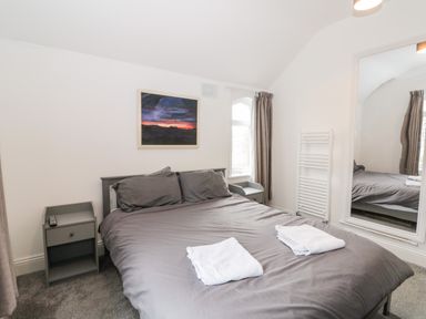 A bedroom with a double bed two bedside tables a window and a large mirror at Castle Manor in Scarborough
