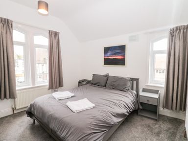 A bedroom with a double bed gray bedding side tables and two windows at Castle Manor in Scarborough