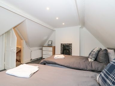 A bedroom with two twin beds a dresser a small fireplace and a staircase at Castle Manor in Scarborough