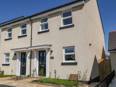 A two storey semi detached house with black doors and several windows at Pebble Bay in Appledore