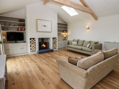 A living room with two sofas a fireplace and a television at Cotswold View in Shipton Under Wychwood