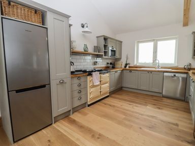 A kitchen with grey cabinets wooden countertops a stainless steel refrigerator dishwasher and a window at Cotswold View in Shipton Under Wychwood