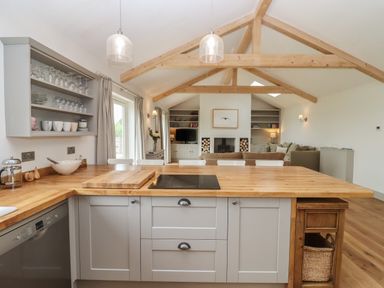 An open kitchen and living area with wooden beams and wooden countertops at Cotswold View in Shipton Under Wychwood
