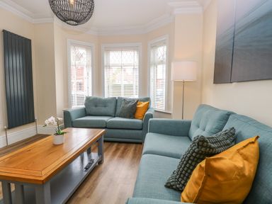 A living room with two blue sofas pillows wooden coffee table and floor lamp at Seaside House in Gorleston-On-Sea