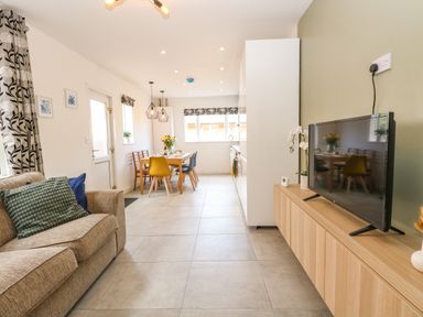 A living room and dining area with a sofa and TV on a wooden cabinet at Seaside House in Gorleston-On-Sea