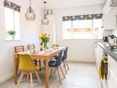 A kitchen with a dining table set with flowers wine and chairs at Seaside House in Gorleston-On-Sea