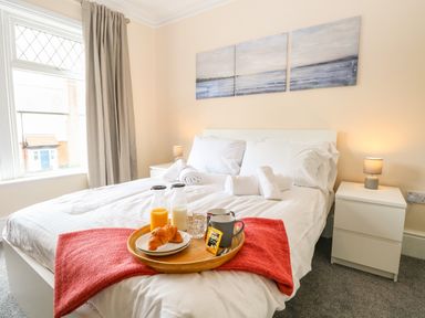 A bedroom with a white bed and bedside tables with lamps and a tray with breakfast at Seaside House in Gorleston-On-Sea