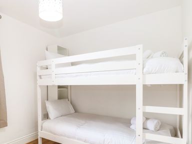 A bedroom with a white bunk bed and rolled towels at Seaside House in Gorleston-On-Sea