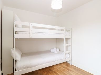 A bedroom with a white bunk bed with white bedding and towels on the lower bed at Seaside House in Gorleston-On-Sea
