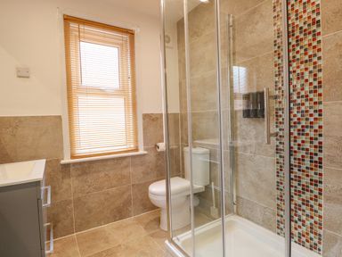 A bathroom with a shower enclosure a toilet a window with blinds and a sink at Seaside House in Gorleston-On-Sea
