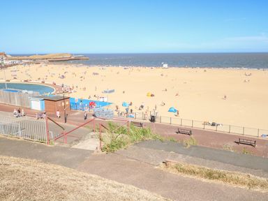A sandy beach with people walking and relaxing near the sea at Seaside House in Gorleston-On-Sea