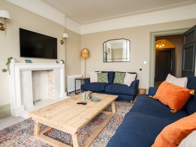 A living room with blue sofas and wooden coffee table at Haulfryn in Barmouth