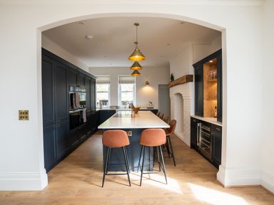 A kitchen with a large island and bar stools under pendant lights at Haulfryn in Barmouth