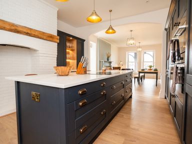 A kitchen with a large island, pendant lights, built-in cabinets, and a dining area with a table and chairs at Haulfryn in Barmouth