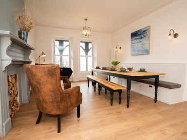 A dining room with a wooden table benches and leather armchairs at Haulfryn in Barmouth