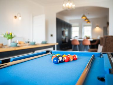 A blue pool table with balls and cues in a room with a dining table and chairs at Haulfryn in Barmouth