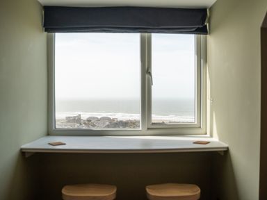 A window with a view of the sea and buildings with a counter and two stools indoors at Haulfryn in Barmouth