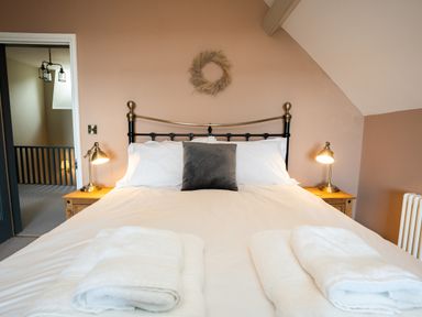 A bedroom with a bed a gray cushion bedside tables with lamps and folded towels at Haulfryn in Barmouth