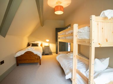 A bedroom with a single bed a bunk bed a bedside table and lamp at Haulfryn in Barmouth