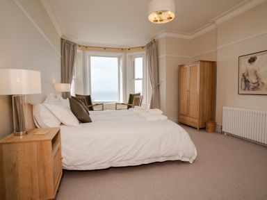 A bedroom with a bed and wooden furniture near a bay window at Haulfryn in Barmouth