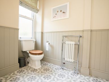 A bathroom with a toilet a radiator a window and patterned floor tiles at Haulfryn in Barmouth