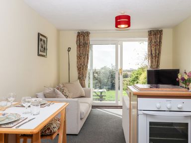 A small living room with a sofa dining table and oven with glass sliding doors at Mabel's View in East Allington Devon
