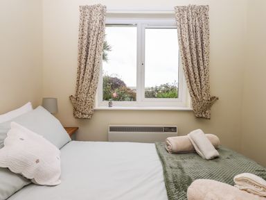 A bedroom with a bed beside a window with curtains and towels on the bed at Mabel's View in East Allington Devon