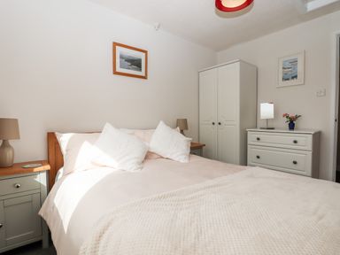 A bedroom with a bed bedside tables lamps wardrobe and chest of drawers at Mabel's View in East Allington Devon